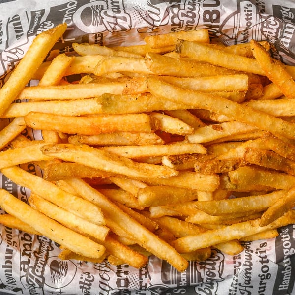 A red basket filled with golden-brown french fries, seasoned and served on branded paper.